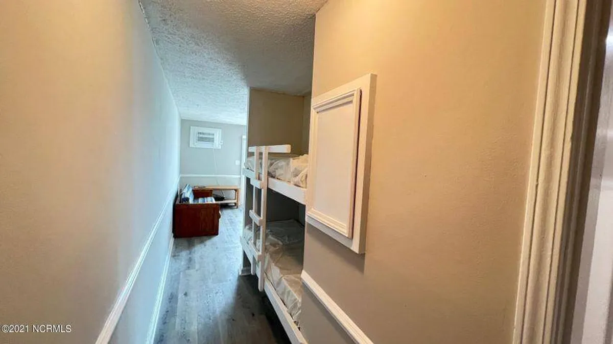A cozy alcove featuring built-in bunk beds with crisp linens and playful decor. A comfortable sofa and framed artwork add warmth and invite a sense of family togetherness in a playful, functional space.