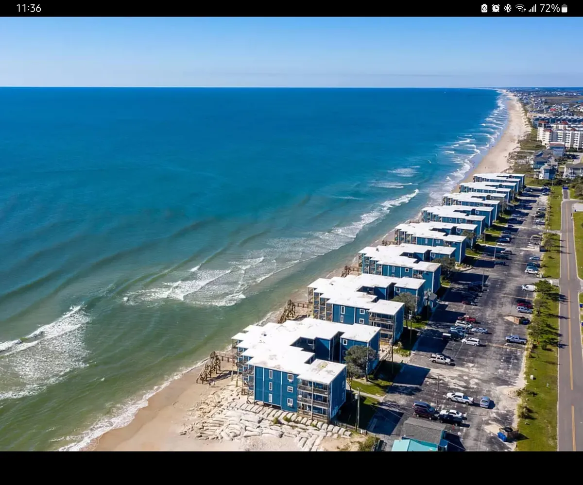 This image features beachfront properties overlooking the ocean waves and a sandy beach, with the vantage point reminiscent of the view from a private balcony. The scene hints at the peacefulness of morning walks and the allure of sunset views, echoing the atmosphere from the condo itself.